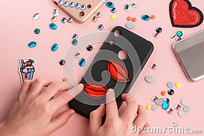 Girl putting red lips patches on black phone case Stock Photo