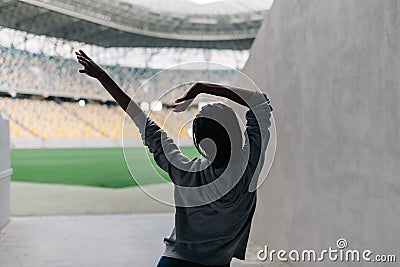 The girl is raising the hands up. The close-up back view of the afro-american teenager. Stock Photo