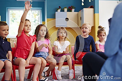 Girl raising her hand to ask question in classroom Stock Photo