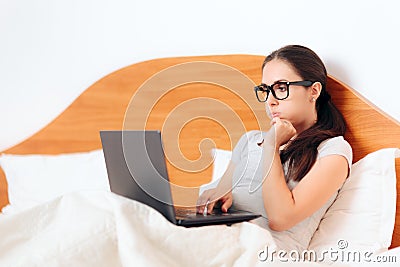 Worried Woman Looking at Laptop Sitting in Bed Stock Photo