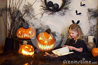 girl reads book spells. Halloween blonde witch. Magic wand in hands of magician. Stock Photo