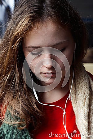 Girl with red-brown hair listening to music with his eyes closed Stock Photo