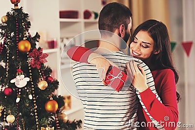 Girl with Red Gift Hugging Boyfriend. Stock Photo