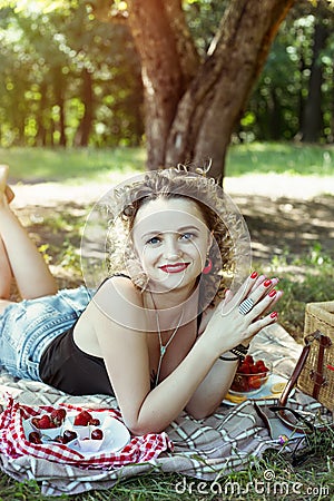 Girl with red lips are eating strawberry on picnic Stock Photo