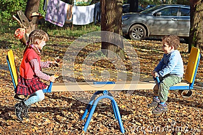 Girl in red vest and her brother on seesaw Stock Photo