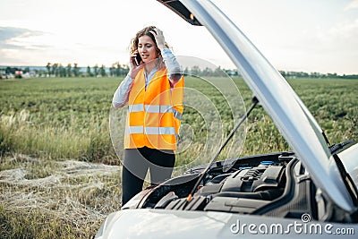 Girl in reflecting vest with phone, broken car Stock Photo