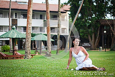 Girl resting on the lawn. bride on honeymoon. hotel territory. relaxation area. woman sitting on a green lawn Stock Photo