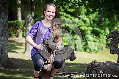 A girl ridding on a wooden horse Stock Photo