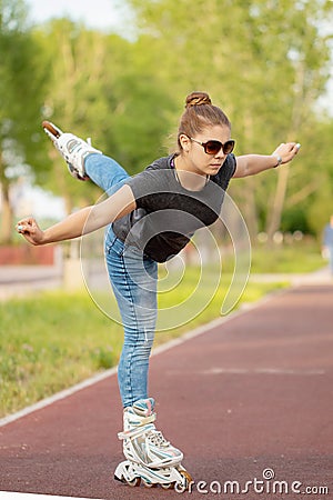 A girl rides roller skates in a city Park in summer Stock Photo