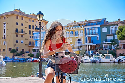 Girl riding a foldable e-bike in a Mediterranean marina Stock Photo