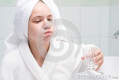 Girl rinses her mouth in the morning with clean water from a glass Stock Photo