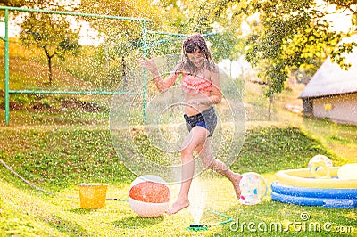 Girl running above a sprinkler, sunny summer back yard Stock Photo