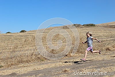 Girl Running in Dirt Field Stock Photo