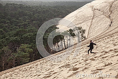 Girl running down the sandy slope of Family of the Pilat Dune Dune du Pyla. Editorial Stock Photo