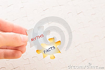 Girl`s hand placing the last jigsaw puzzle piece with word Facts and Myths Stock Photo