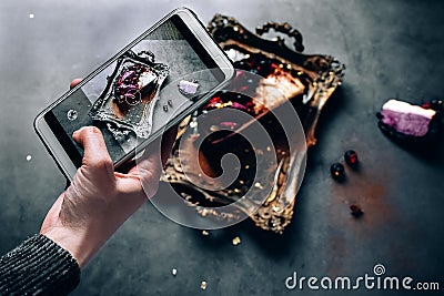 Girl`s hand shoots food dessert on the phone. chocolate souffle pudding cake filled with fresh berries on the Golden tray Stock Photo