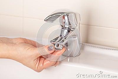 The girl`s hand twists off twists the faucet aerator in the bathroom Stock Photo