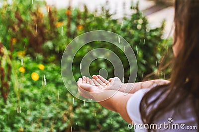 Girl`s hands catching raindrops on blurred green floral background Stock Photo