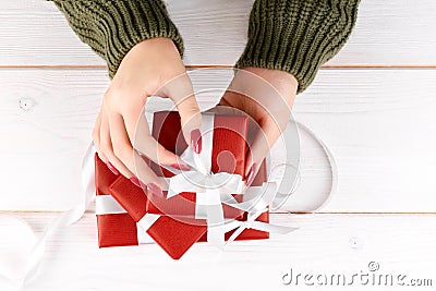 Girl`s hands unwrapping Christmas, birthday or Valentines red gift on a white background Stock Photo