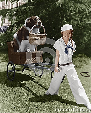 Girl in sailor suit pulling dog in basket Stock Photo