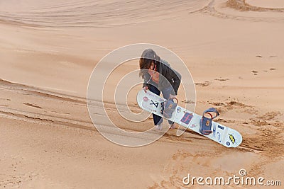 Girl sand boarding in desert Stock Photo