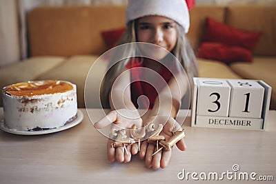 Girl in Santa hat shows burnt candles of numbers of outgoing year in her palms, festive background Stock Photo