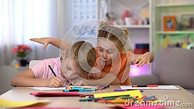 Girl scaring brother studying at table, child hyperactivity, attention deficit Stock Photo