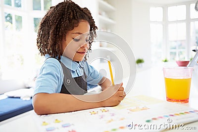 Girl In School Uniform Doing Homework In Kitchen Stock Photo