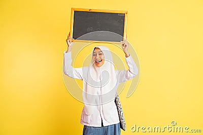 girl in school uniform in veil carrying black chalkboard up Stock Photo