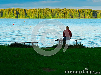 Girl seating on the bench on river bank background Stock Photo