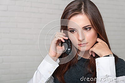 Girl secretary speaks by phone dropping his gaze pensively Stock Photo