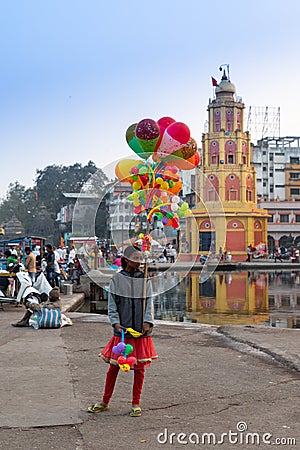 A girl selling colorful balloon arts near bank of Godavari river, Nashik City, Maharashtra, India, crowded by local people, Editorial Stock Photo