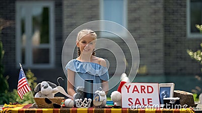 Girl selling old toys on yard sale, earning pocket money, young business lady Stock Photo
