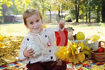 Girl showing red busket under autumn trees Stock Photo