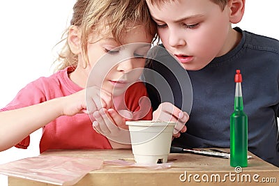 Girl shows brother how to sow grains in pot Stock Photo