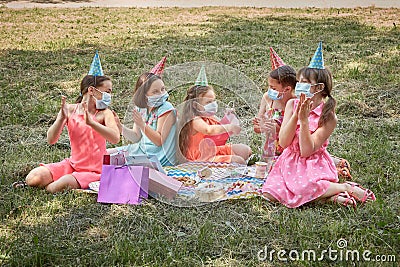 The girl shows a gift to a friend. Birthday in a medical mask. Stock Photo