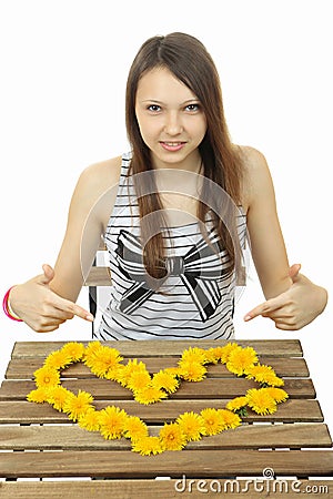 Girl shows the heart of wildflowers. Heart of yellow dandelions. Stock Photo