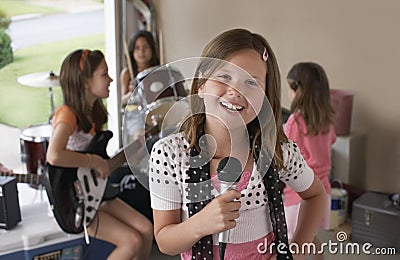 Girl Singing Into Microphone With Friends Playing Musical Instrument Stock Photo