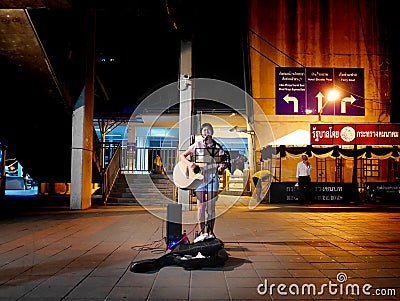 Girl singing and playing guitar in Bangkok Editorial Stock Photo
