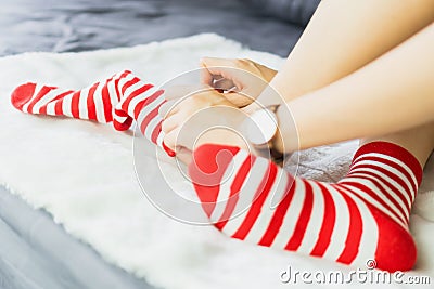The girl sit on a white carpet and put on socks, white punctuate red side. Stock Photo