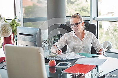 Girl siting in an office chair and checking contracts and documents. Office worker. Business woman. Stock Photo