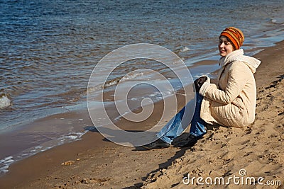 Girl sits on beach, an autumn sunny day Stock Photo