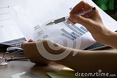 The girl sits at her desk and draws up graphs and histograms about income, business and finance, planning , economics Stock Photo