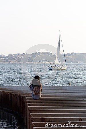 Lonely Girl and a Sailboat Editorial Stock Photo