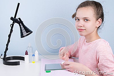 The girl sits at the table and puts on a contact lens to improve vision Stock Photo