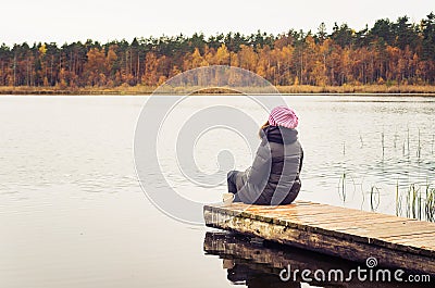 Girl sitting alone on a peaceful footbridge in the middle of nowhere Stock Photo