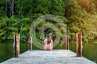 Girl sitting alone on a the wooden bridge on the lake. Pang Ung, Thailand Stock Photo