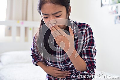 Young Girl Sitting On Bed At Home Feeling Nauseous Stock Photo