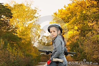 Girl sitting on the bike. walk in the autumn. riding on the road Stock Photo