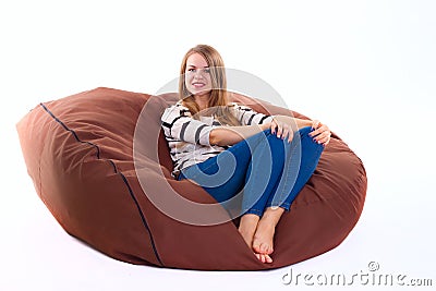 Girl sitting on a braun beanbag chair. Stock Photo